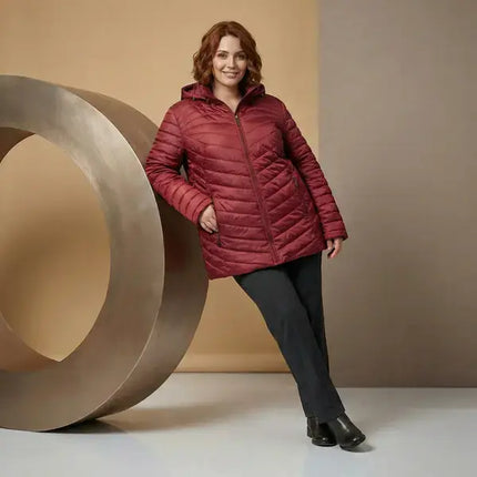 Жена носеща бордо ватирано яке в размер 8XL комбинирано с тъмен панталон в студио с топъл фон и кръгъл декоративен елемент