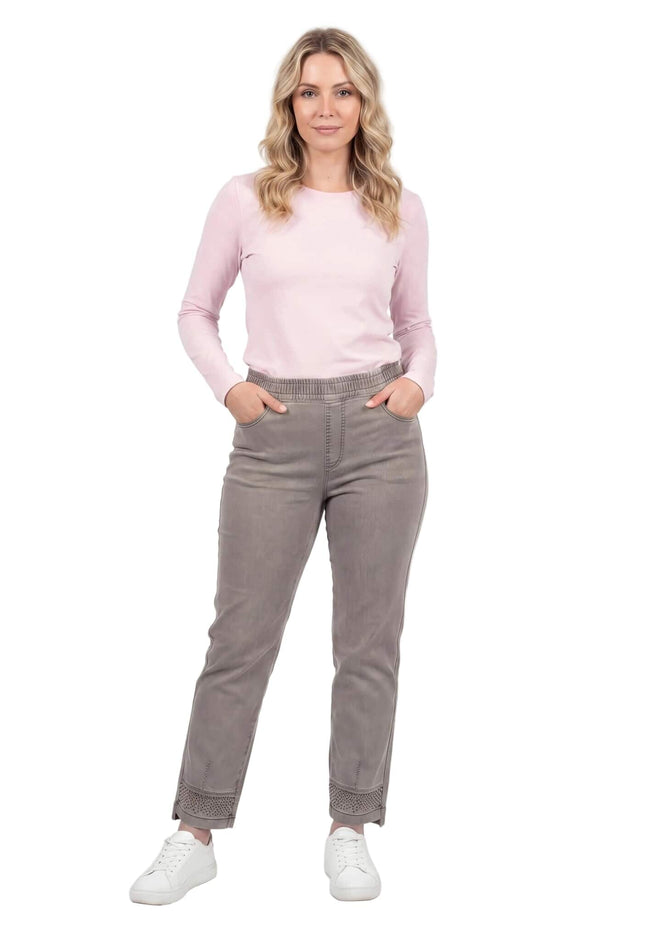 Бежови дамски дънки големи размери с права кройка и декорация от камъчета по крачолите. Показани в цял ръст на бял фон, съчетани с розова блуза.