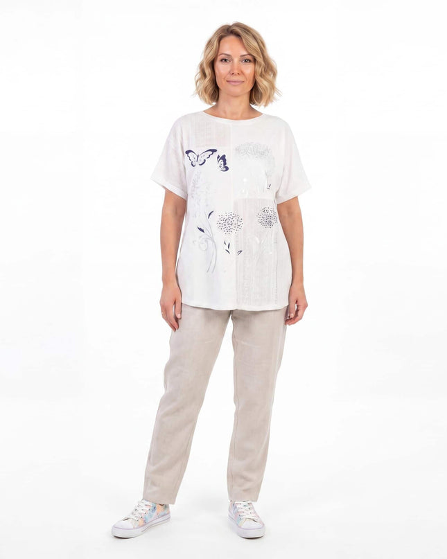 Бяла лятна памучна туника големи размери с флорална апликация и дантела, представена от модел в цял ръст.