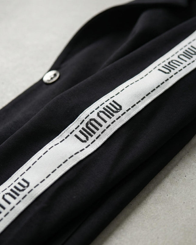 Детайл отблизо на декоративен бял кант с надписи върху ръкава на черен ежедневен дамски комплект големи размери.