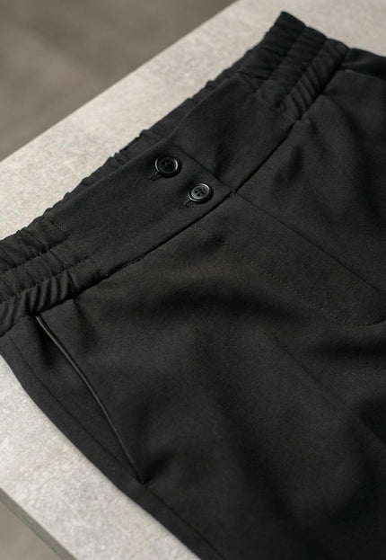 Детайл отблизо на талията на черен официален дамски панталон, показващ закопчаване с две копчета и еластични елементи отстрани за комфорт.