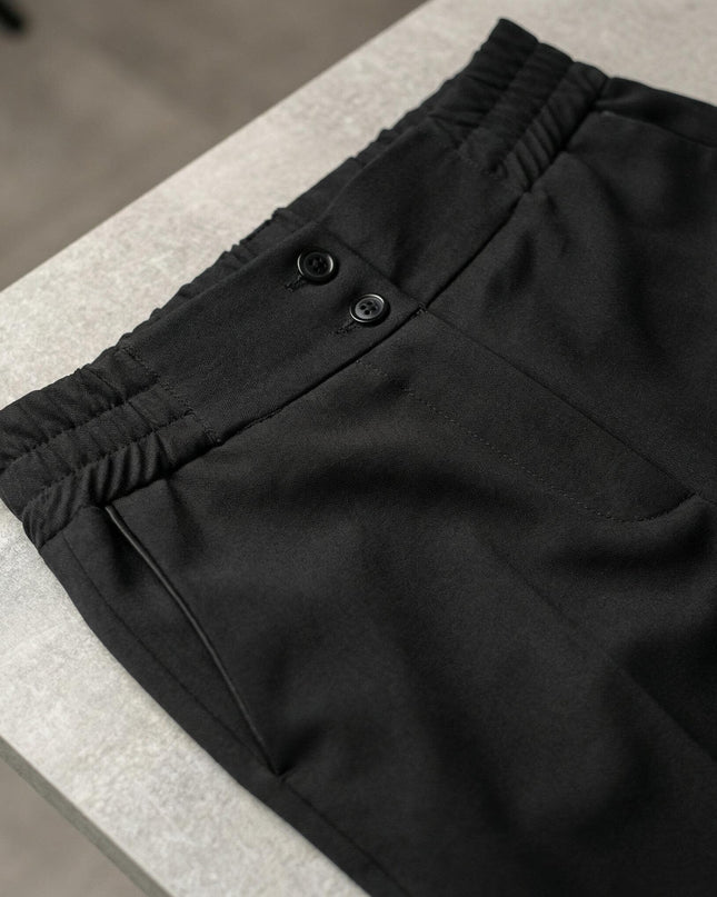 Детайл отблизо на талията на черен официален дамски панталон, показващ закопчаване с две копчета и еластични елементи отстрани за комфорт.