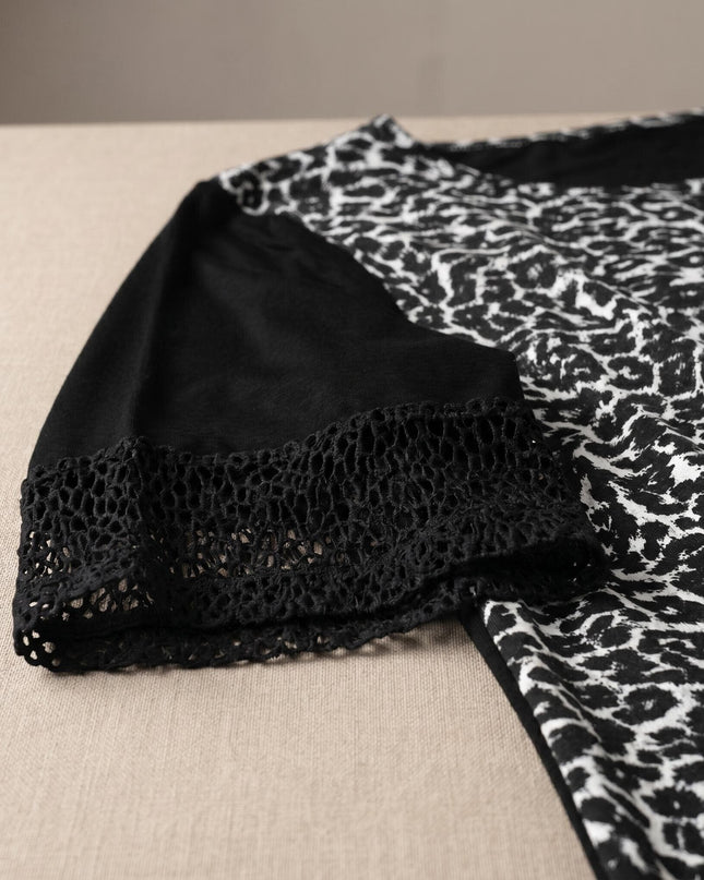 Детайл отблизо на черна лятна макси туника, показващ ръкава с декоративен елемент от фина мрежа и контрастния черно-бял десен.