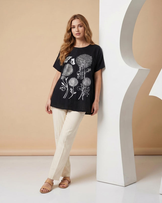 Черна лятна макси туника с ефектна апликация на цветя, заснета в цял ръст на модел, комбинирана със светъл панталон.