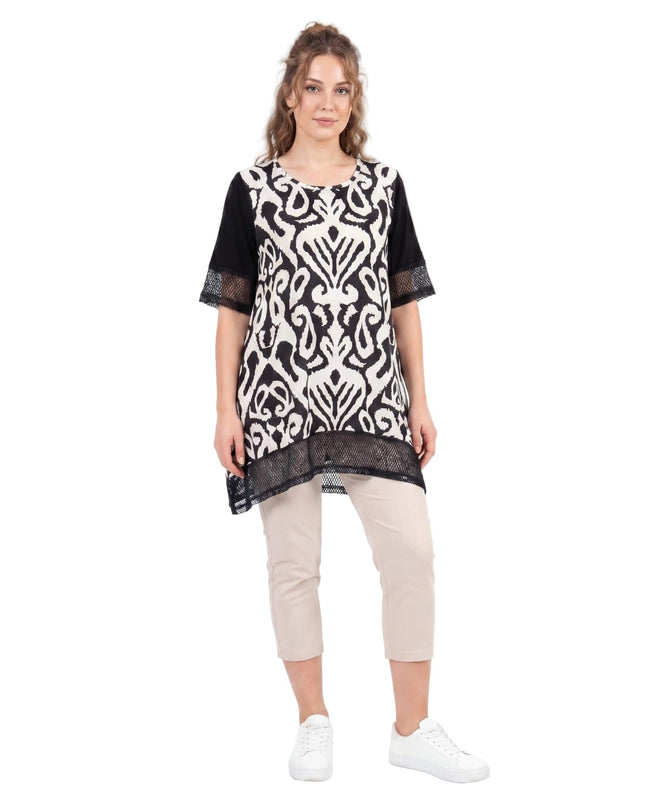 Черна лятна туника с абстрактен принт и мрежести елементи по късите ръкави и подгъва. Моделът е представен в цял ръст със светли панталони.