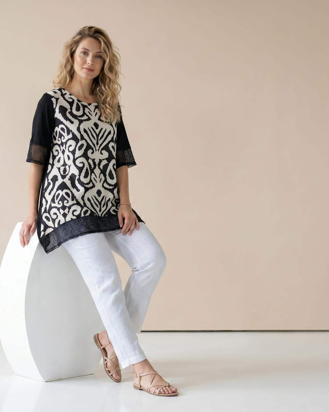 Модел в цял ръст, облечен в черна лятна туника големи размери с ефектен черно-бял абстрактен принт и нежни мрежести елементи по краищата.