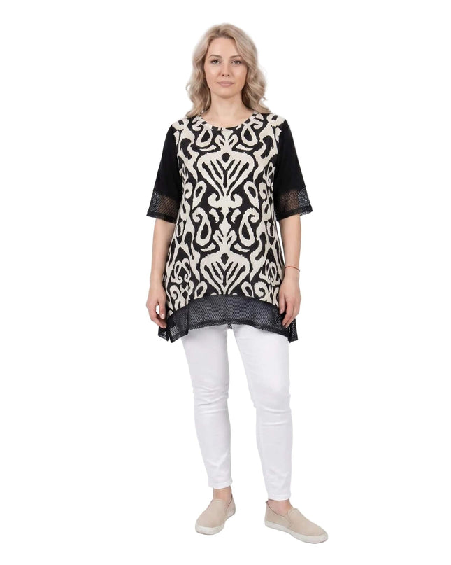 Черна лятна туника големи размери с мрежести елементи, заснета в цял ръст на бял фон отпред. Моделът позира с бял панталон и бежови обувки.