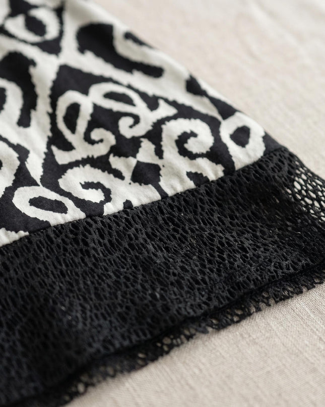 Детайл отблизо на черна лятна туника големи размери, показващ ефектния черно-бял принт и мрежестия кант по подгъва.