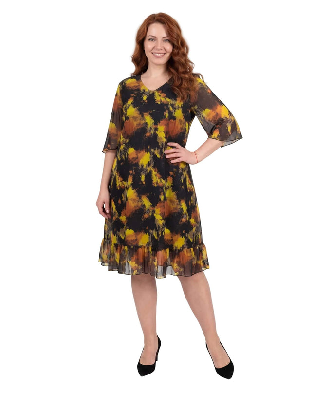 Черна официална шифонена рокля големи размери с жълт принт и волан на подгъва. Снимка в цял ръст, разкриваща елегантния силует и разкроените ефирни ръкави.