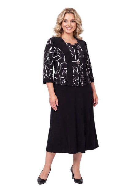 Черна официална рокля големи размери с красива брошка и ефектен листен мотив в горната част, заснета отпред в цял ръст на бял фон.