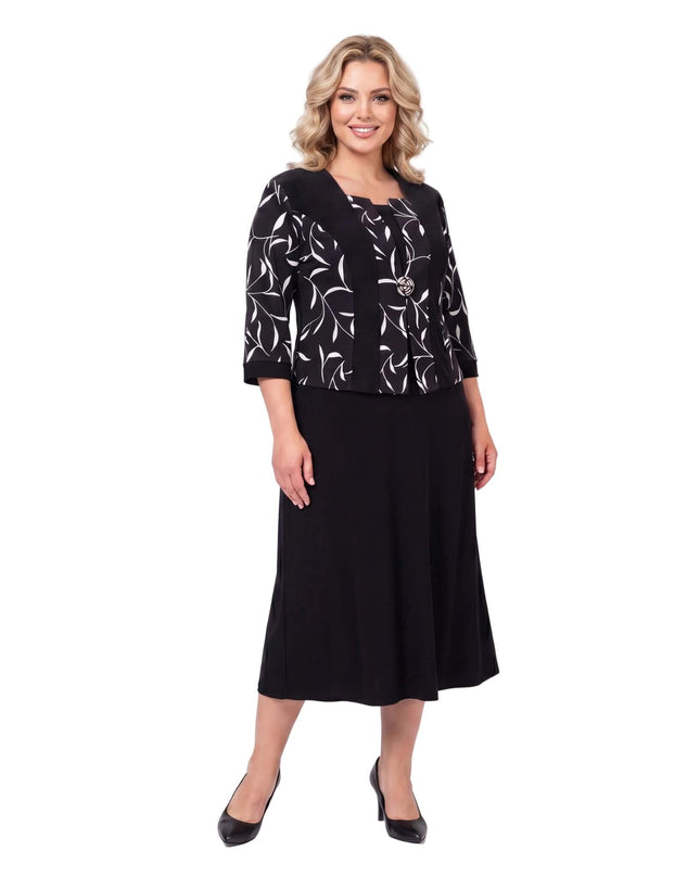 Черна официална рокля големи размери с красива брошка и ефектен листен мотив в горната част, заснета отпред в цял ръст на бял фон.