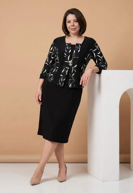 Черна официална рокля големи размери с красива брошка и ефектен бял листен мотив, показана в кадър цял ръст върху модел.