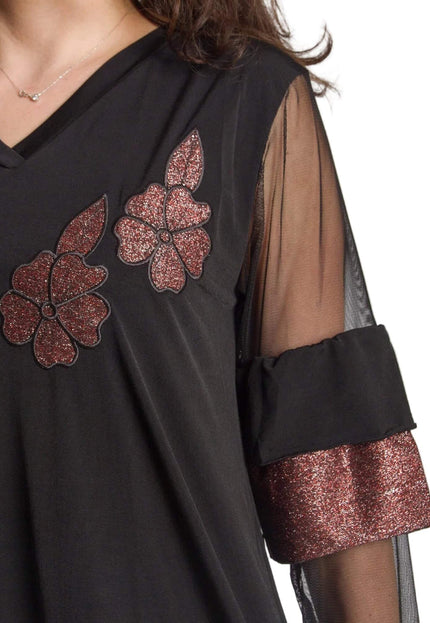 Детайлен кадър на черна официална туника, показващ блестящи цветя в бордо и тюлен ръкав с широк маншет с металически ефект.