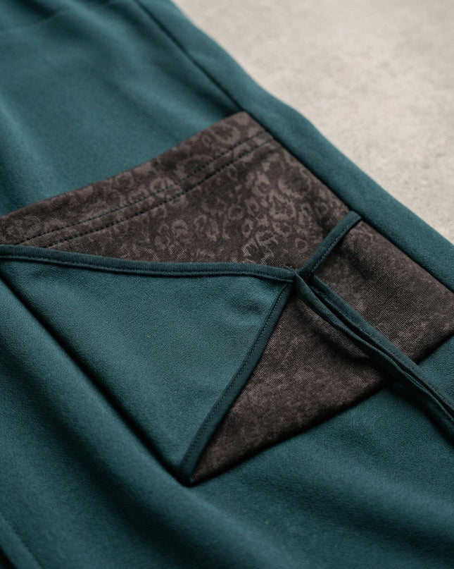 Детайлен кадър на масленозелен макси елек, показващ джоб с ефектен акцент от еко кожа и връзки за регулиране.