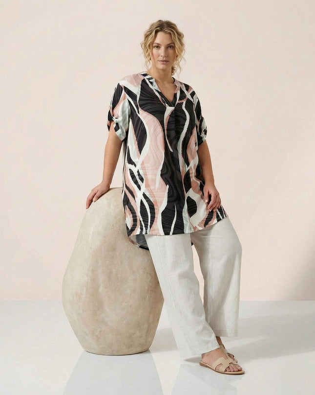 Дълга лятна макси туника с абстрактен шарен принт, V-образно деколте и асиметрична кройка, представена от модел в цял ръст.