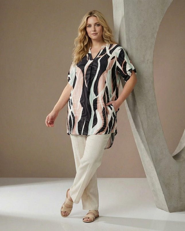 Дълга лятна макси туника с шарен абстрактен принт и асиметрична кройка. Кадър в цял ръст на модел, показващ съчетание с летен панталон.