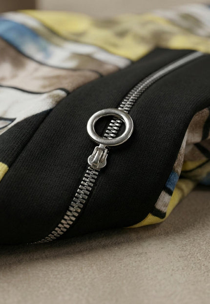 Детайл отблизо на сребристия цип с кръгъл плъзгач и абстрактния цветен принт на удобна дълга макси туника, показващ меката материя.