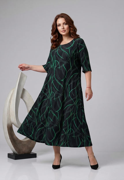 Кадър в цял ръст на дълга официална макси рокля в черно със зелен абстрактен линеен принт. Елегантен модел с къс ръкав и свободно падащ силует.