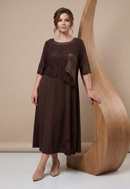 Дълга официална макси рокля в кафяво с ефектни дантелени детайли, представена в цял ръст до дървена декорация.
