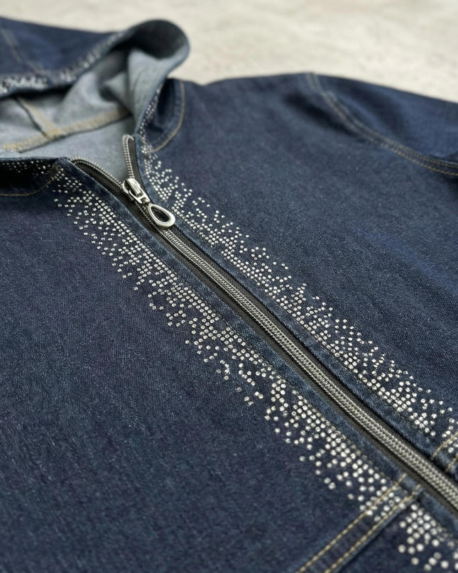 Детайл отблизо на тъмносиньо дънково яке с качулка. Ясно се виждат предният цип и ефектните декоративни камъчета, разположени по дължината му.