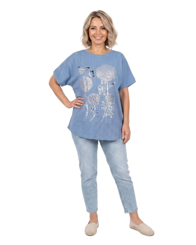 Дамска лятна синя туника големи размери със сребриста флорална апликация. Снимка в цял ръст, показваща стилната ежедневна визия с дънки.