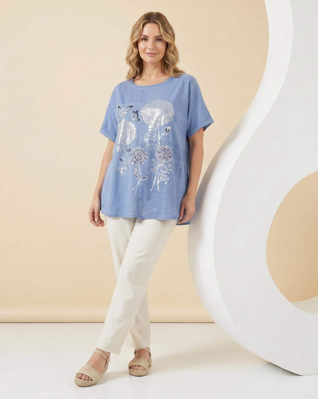 Дамска лятна синя туника големи размери със сребриста флорална апликация и къси ръкави, представена в цял ръст.