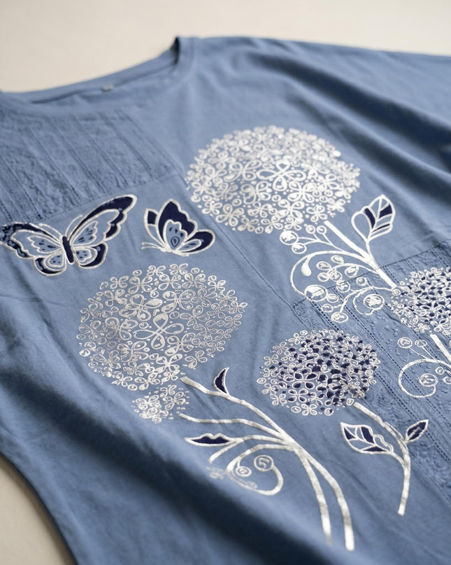 Детайл отблизо на лятна синя туника големи размери, показващ ефектната сребриста флорална апликация с пеперуда на предната част.