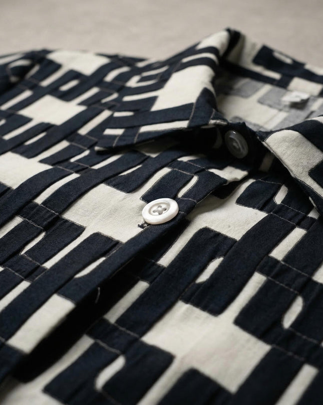 Детайл отблизо на дамска макси риза, разкриващ интересен черно-бял геометричен десен, класическа яка и бяло копче.