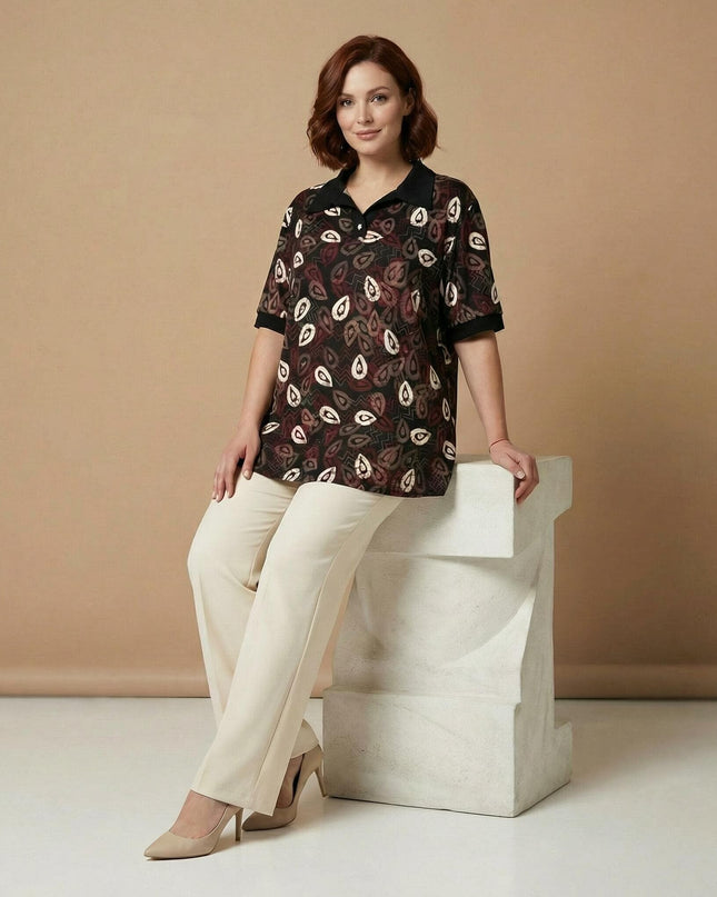 Дамска официална туника в черен цвят с красив десен на листа и контрастна яка. Представена в цял ръст на модел, позиращ до декоративна колона.