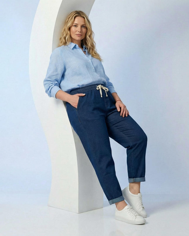 Тъмносини дамски прави еластични дънки големи размери с ластик и бели връзки на талията, представени в кадър в цял ръст.