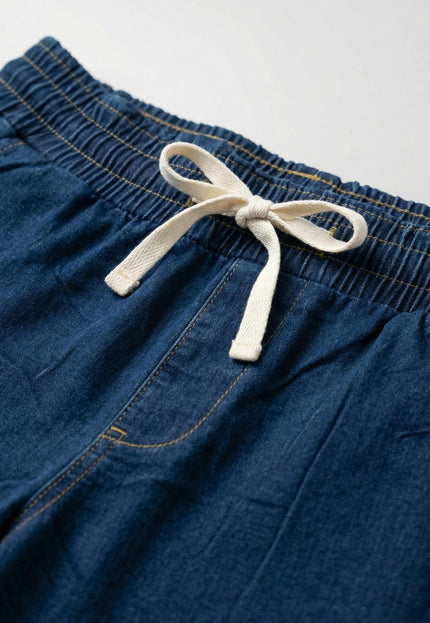 Детайл отблизо на дамски еластични дънки в син цвят. Фокус върху удобния ластик в кръста с бяла връзка за регулиране и класически жълти шевове.