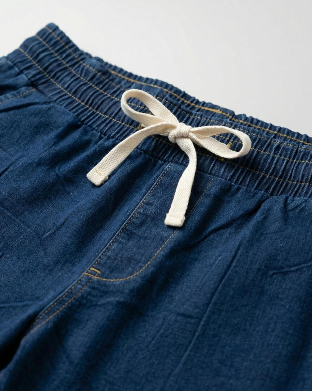 Детайл отблизо на дамски еластични дънки в син цвят. Фокус върху удобния ластик в кръста с бяла връзка за регулиране и класически жълти шевове.