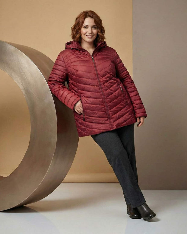 Жена носеща бордо ватирано яке с качулка в голям размер в студио с топъл бежов фон и декоративен кръгъл елемент