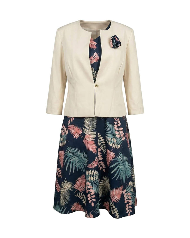 Елегантен дамски костюм големи размери, съчетаващ тъмносиня рокля с цветни мотиви и стилно бежово сако с брошка, заснет на бял фон.
