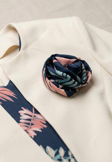 Детайл отблизо на бежово сако с декоративно цвете от плат към елегантен дамски костюм с рокля на цветя.