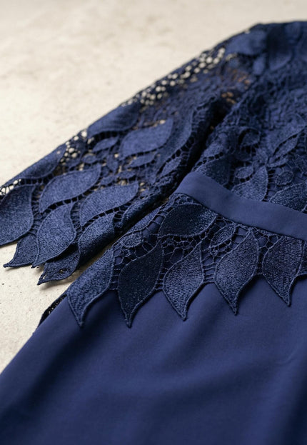 Детайл отблизо на елегантна тъмносиня макси рокля, акцентиращ върху дантеления ръкав с мотиви на листа и назъбен край.