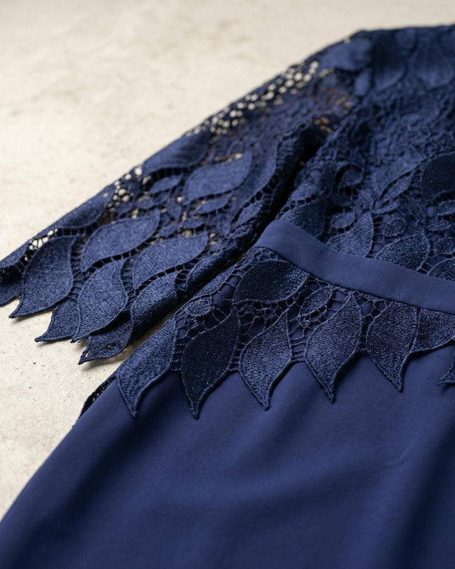 Детайл отблизо на елегантна тъмносиня макси рокля, акцентиращ върху дантеления ръкав с мотиви на листа и назъбен край.