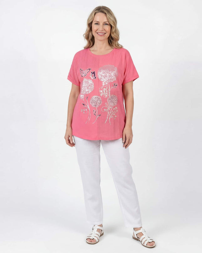 Цял ръст: Ежедневна лятна макси туника в корал с обло деколте, къси ръкави, флорални мотиви и разкроена кройка, облечена от модел на бял фон.