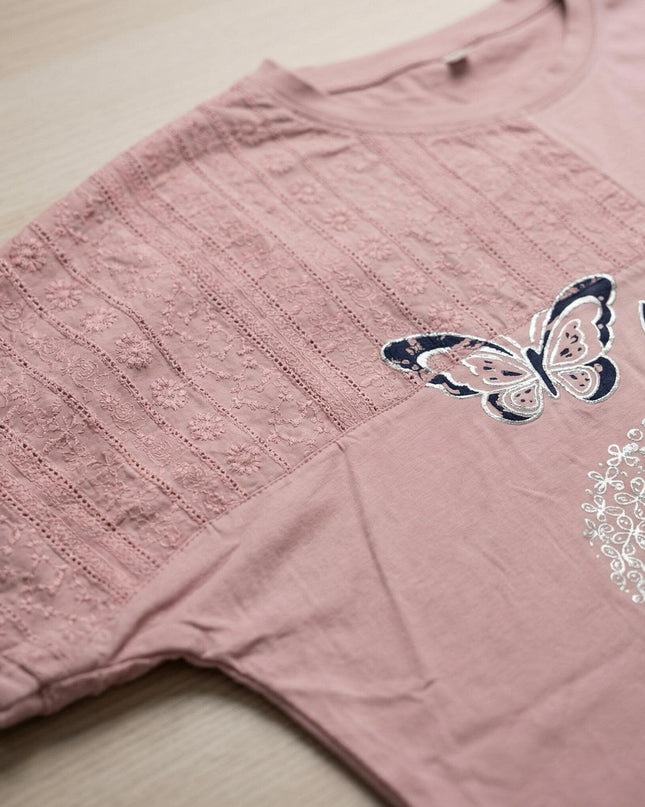 Детайл отблизо на лятна памучна туника в розово, показващ апликации на пеперуди, декоративен принт и елегантни панели от бродирана мрежа.