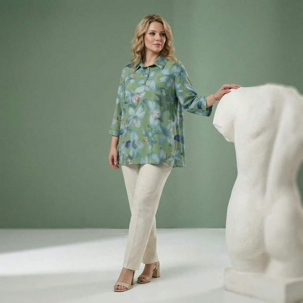 Дама със зелена флорална туника и светъл панталон в елегантна студийна среда
