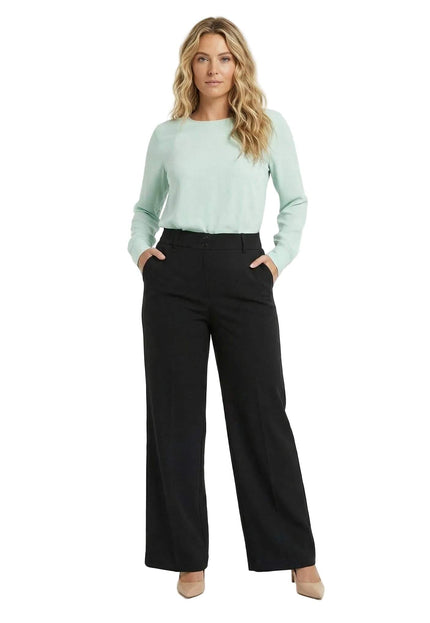 Студийна снимка в цял ръст на официален черен панталон големи размери с права кройка, съчетан със светлозелена блуза и бежови обувки на висок ток.