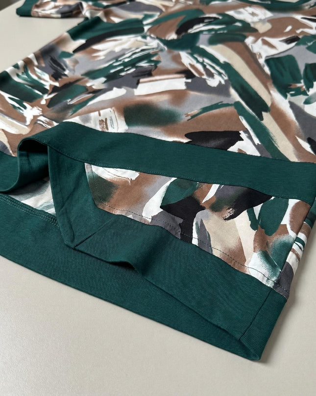 Детайл отблизо на асиметричния подгъв в масленозелено на официална макси туника с абстрактен принт.