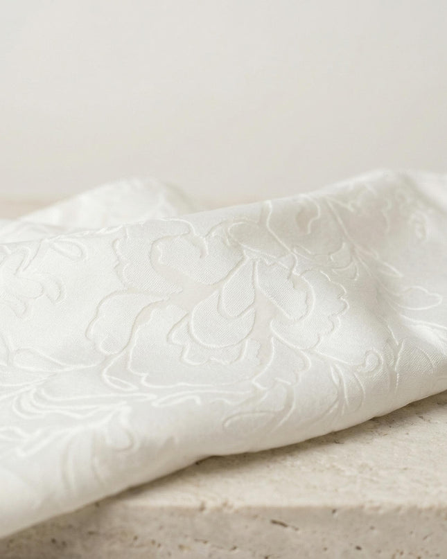 Детайл отблизо на официална бяла макси туника с красив релефен флорален десен тип деворе.