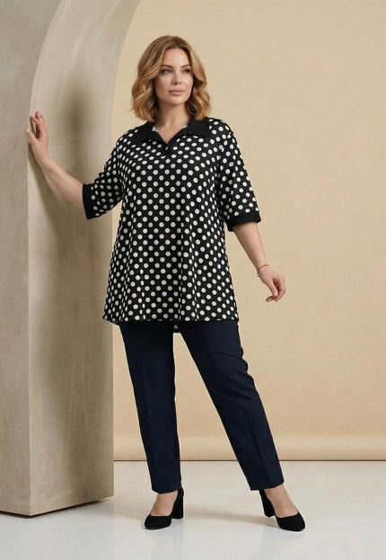 Елегантна визия в цял ръст с официална черна макси туника на бели точки, завършена с черна яка и къси ръкави с плътни маншети.