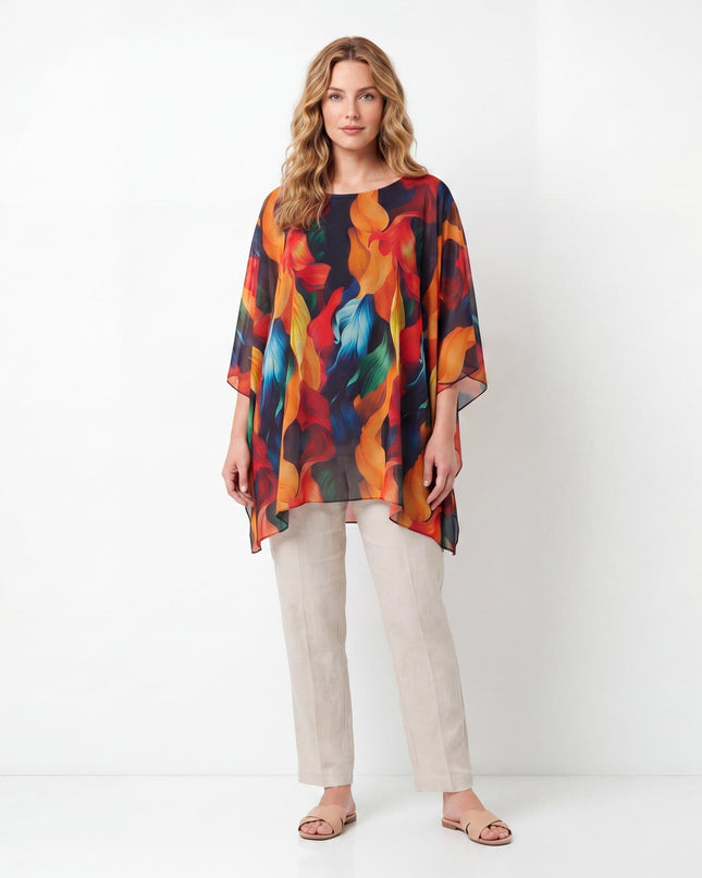 Кадър в цял ръст на лятна макси туника тип пончо, съчетана със светъл панталон. Дрехата се отличава с ефирна кройка и ярък пъстър десен.