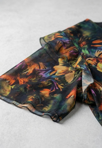 Детайл на ефектния ръкав на официална макси рокля от цветен шифон, показващ абстрактния принт и вълнообразния подгъв.