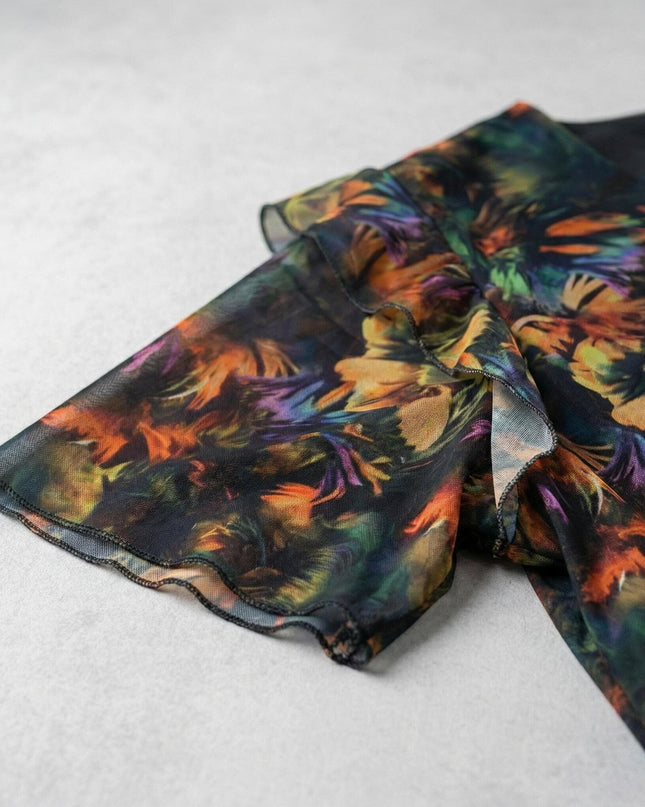 Детайл на ефектния ръкав на официална макси рокля от цветен шифон, показващ абстрактния принт и вълнообразния подгъв.