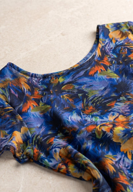 Детайл отблизо на официална макси рокля от пъстър шифон. Плосък кадър, показващ деколтето и ефирната материя с абстрактен флорален принт.