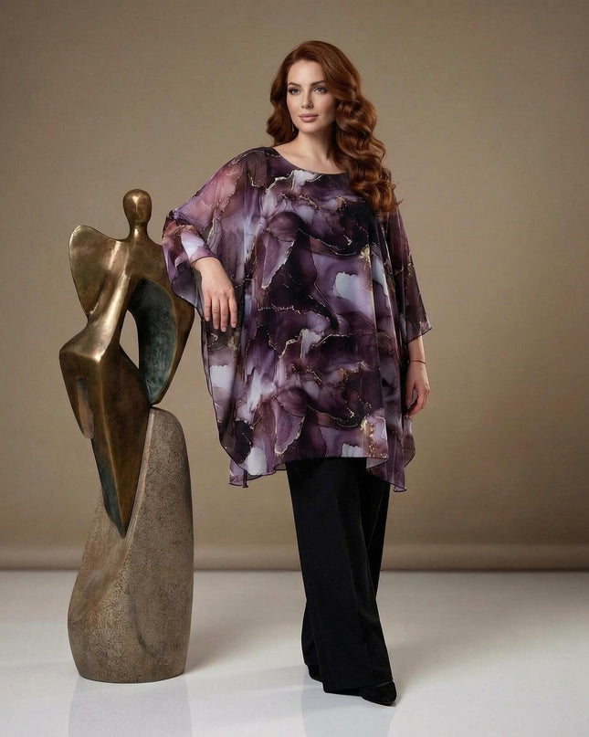Официална макси туника тип пончо в лилави нюанси с мраморен принт и ефирен шифон. Кадър в цял ръст до абстрактна статуя.