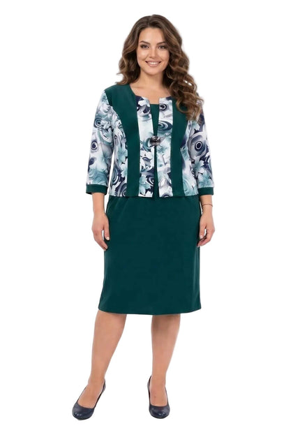 Официална масленозелена рокля за едри дами, с ефектен флорален десен и брошка, заснета в цял ръст.